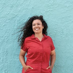 white woman with long brown hair in front of a blue wall